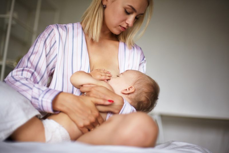 kobieta karmi dziecko piersia na lozku