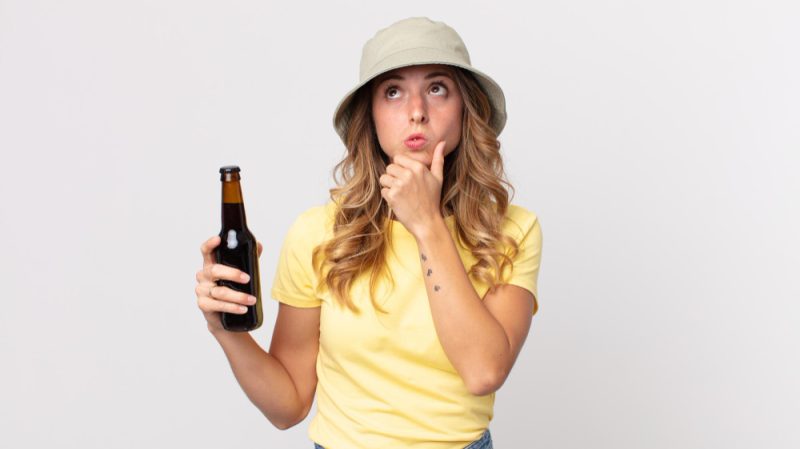 kobieta trzyma butelke z piwem