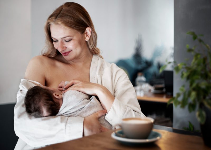 kobieta karmi dziecko piersia i pije herbate mietowa